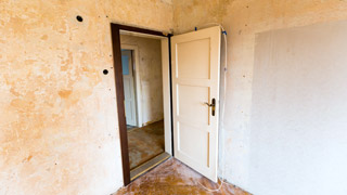 Eine renovierungsbedrftige Wohnung mit vergilbter Wand und schmutzigem Boden