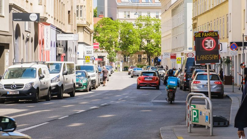 copyright: BV 6/Daniel Dutkowski Blick auf eine schmale Straße zwischen hohen Gebäuden, rechts und links parken vile Autos; Am Straßenende stehen 3 Bäume.