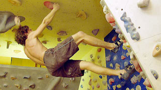 a climber hanging head down from a climbing wall