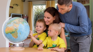Parents look at a globe with two boys