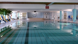 Schwimmbecken im Hallenbad Grofeldsiedlung mit Liegesthlen an der Seite