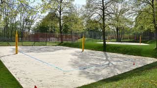 Volleyballplatz mit Sand und Netz, im Hintergrund ein weiterer Volleyballplatz