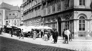 Historisches Schwarz-Wei-Foto: mit Schirmen berdachte Marktstnde, davor reges Treiben