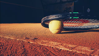 Tennisball und Tennisschlger auf rotem Sandboden