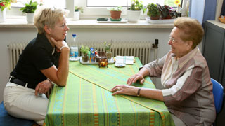Eine jngere und eine ltere Frau sitzen an einem Tisch.
