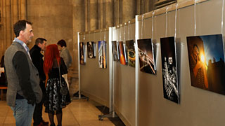 Menschen vor Ausstellungswnden mit Fotos