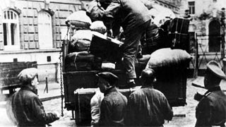 A member of the SS oversees the loading of the luggage of Viennese Jews singled out for deportation