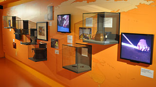 Orange coloured wall with exhibits in glass cases.