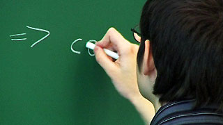A young man writing on a blackboard