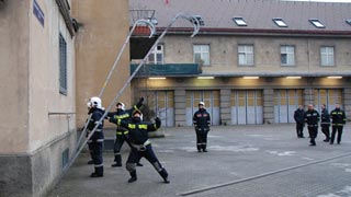 Feuerwehrmnner, die eine Hakenleiter an der Wand anlehnen