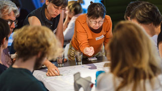 Menschen rund um einen Tisch beugen sich ber einen Straenplan und diskutieren Potentiale fr eine Umgestaltung des ffentlichen Raums