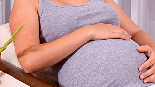 Schwangere Frau sitzt in einem Polstersessel