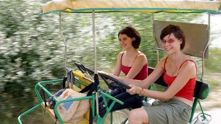Zwei junge Frauen fahren mit einer Rikscha