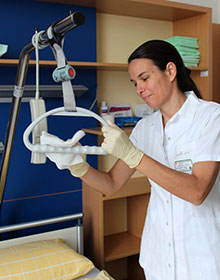 Eine Frau desinfiziert den Griff zum Aufziehen fr Patienten oberhalb eines Krankenbettes