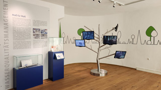 Ausstellungsraum mit Schauksten und Bildschirmen