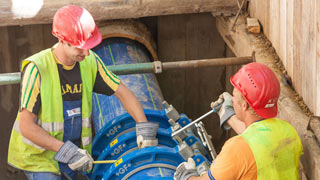 Zwei Mitarbeiter von Wiener Wasser ziehen ein neues Rohr in ein altes Rohr ein