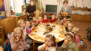 Kinder, die rund um einen Tisch sitzen und essen