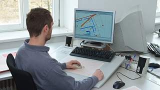 Ein Mann digitalisiert Plne vor einem Computer