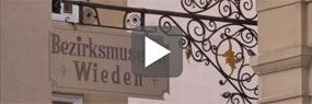 Videoausschnitt mit Play-Button: Schild mit der Aufschrift "Bezirksmuseum Wieden"