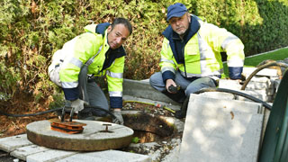 Dva radnika kanalizacije sede ispred septičke jame 