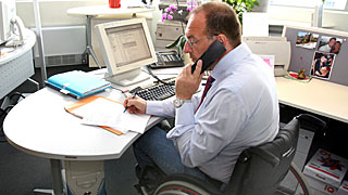 Čovek u invalidskoj stolici radi u birou