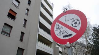 Znak zabrane voženja bicikla, igranja nogometa itd; u pozadini stambena
