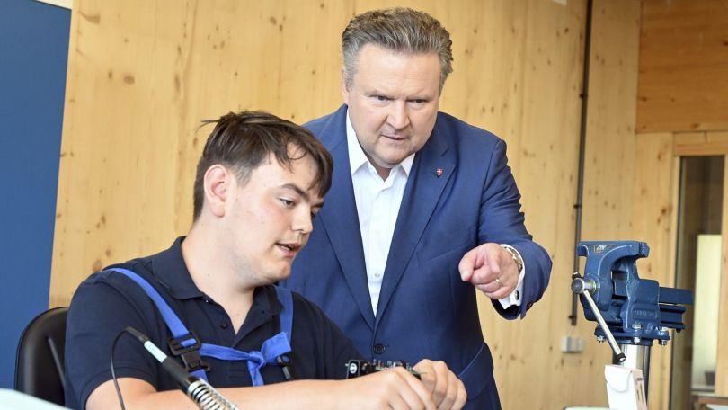 Michael Ludwig sieht einem Lehrling in einer Werkstätte beim Arbeiten zu.