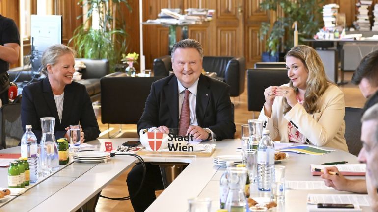 copyright: Stadt Wien / Christian Jobst 2 Politikerinnen sitzen neben einem Politiker an einem U-förmigen weißen Tisch mit Getränken, im Hintergrund schwarze Ledermöbel.