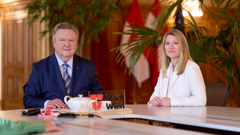 Michael Ludwig und Bettina Emmerling sitzen an einem großen Besprechungstisch im Rathaus.