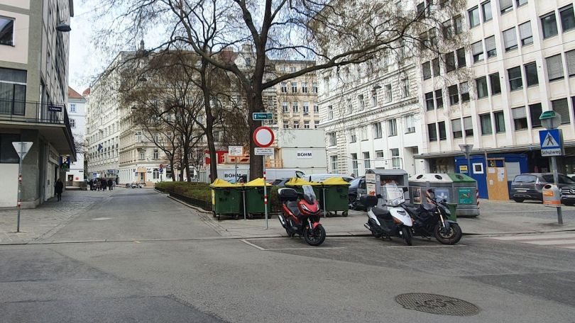 copyright: BV 1 Platz mit Bäumen in der Mitte, rundherum Altbauten, Gehweg, Straße und parkende Mopeds.