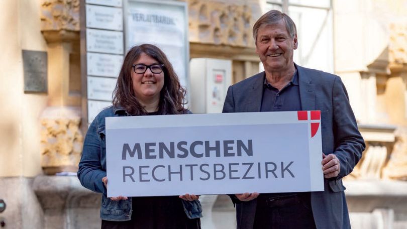 Bezirksvorsteher Erich Hohenberger und Bezirksrätin Irini Tzaferis halten ein Schild mit der Aufschrift "Menschenrechtsbezirk"