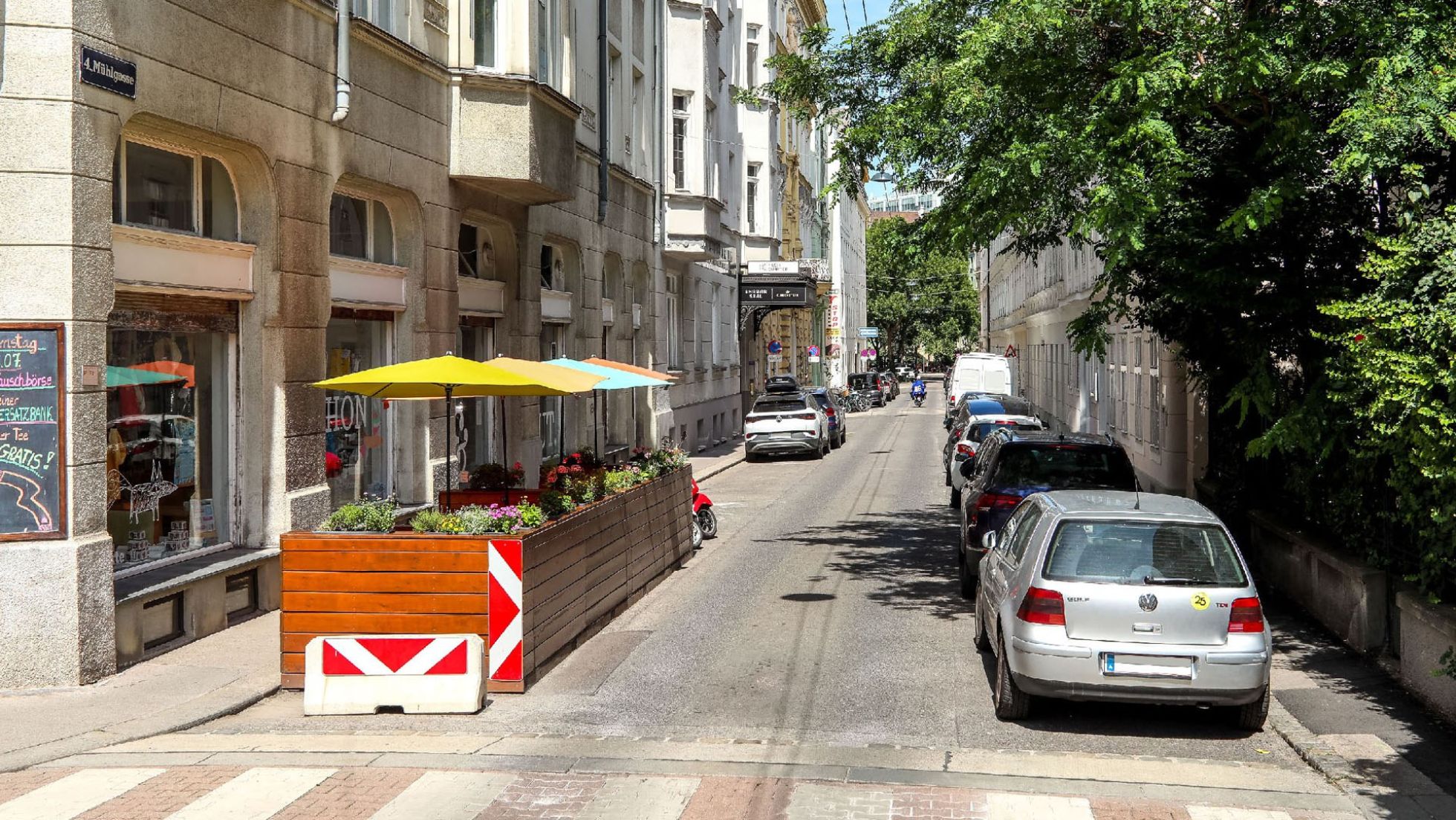Ein Schanigarten und parkende Autos in der Mühlgasse