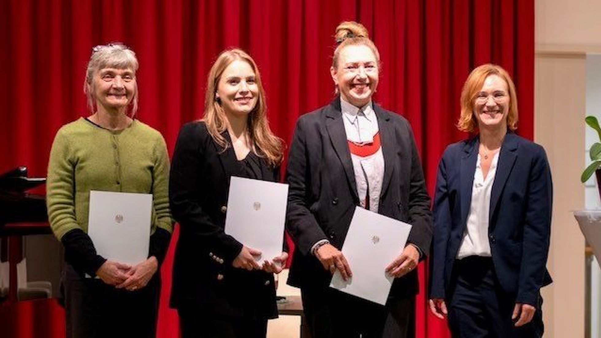 copyright: Bezirksvorstehung Wieden 4 Frauen stehen mit Urkunden vor einem roten Vorhang