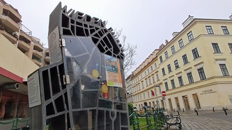 Offener Bücherschrank auf einem Platz vor 2 Wohnhäusern