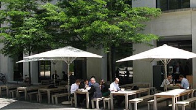 Schanigarten unter Bäumen und Sonnenschirmen