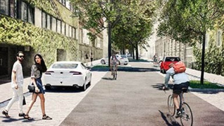 Fahrradfahrer und Fußgängerinnen in einer verkehrsberuhigten Straße