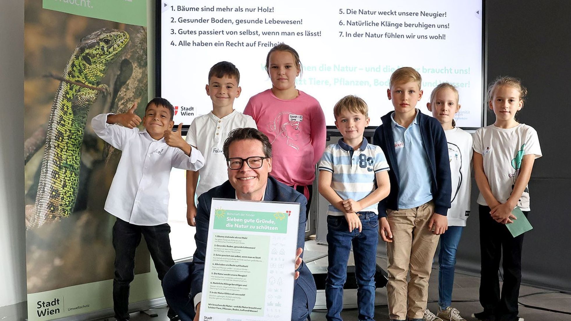 Stadtrat Jürgen Czernohorszky mit Kindern vor einer Präsentation bei der Kinder-Biodiversitäts-Konferenz.