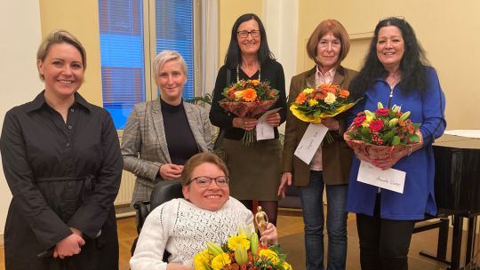 6 Frauen; 4 davon halten einen Blumenstrauß in den Händen; eine der Preisträgerinnen sitzt im Rollstuhl