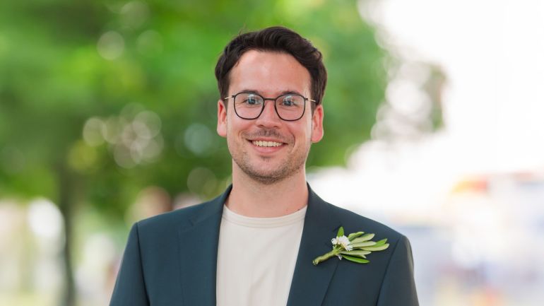 Ein lächelnder Mann mit kurzen brauen Haaren und Brille