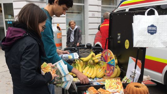 2 junge Leute vor einer mobilen Station mit Bananen und anderen Lebensmitteln