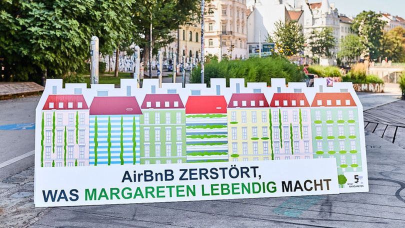 Großer Aufsteller mit gezeichneten bunten Häusern, darunter der Text "AirBnB zerstört was Margareten lebendig macht"
