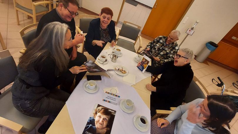 Ältere Frauen und Männer sitzend lachend um einen Tisch