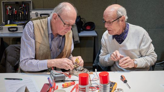 2 ältere Herren reparieren ein elektrisches Gerät