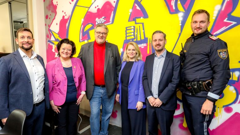 Markus Rumelhart, Peter Hacker und Gäste bei der Eröffnung des LAB65; sie posieren vor einer Wand, die mit dem Graffito LAB65 bemalt ist