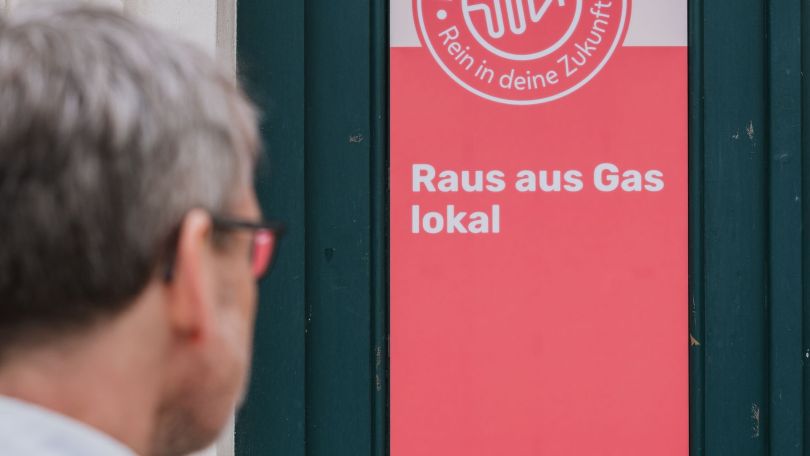 Ein Mann steht vor einer Infotafel mit der Aufschrift "Raus aus Gas lokal"