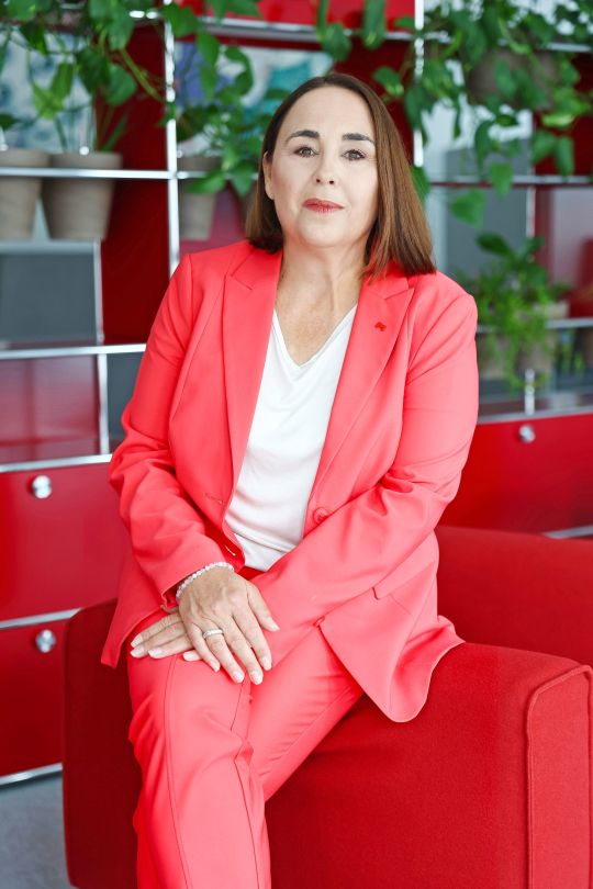 copyright: Rene Wallentin Julia Lessacher sitzt auf der Armlehen eines roten Fauteuils und trägt einen rosafarbenen Hosenanzug