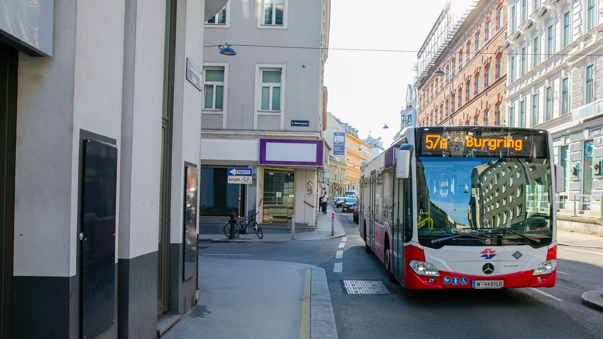 Bus der Linie 57A Richtung Burgring auf einer Straße zwischen Gebäuden