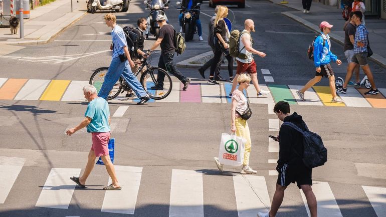 Menschen überqueren eine Kreuzung mit buntem Zebrastreifen