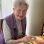 Eine ältere Dame malt mit Pinsel an einem bunten Bild
