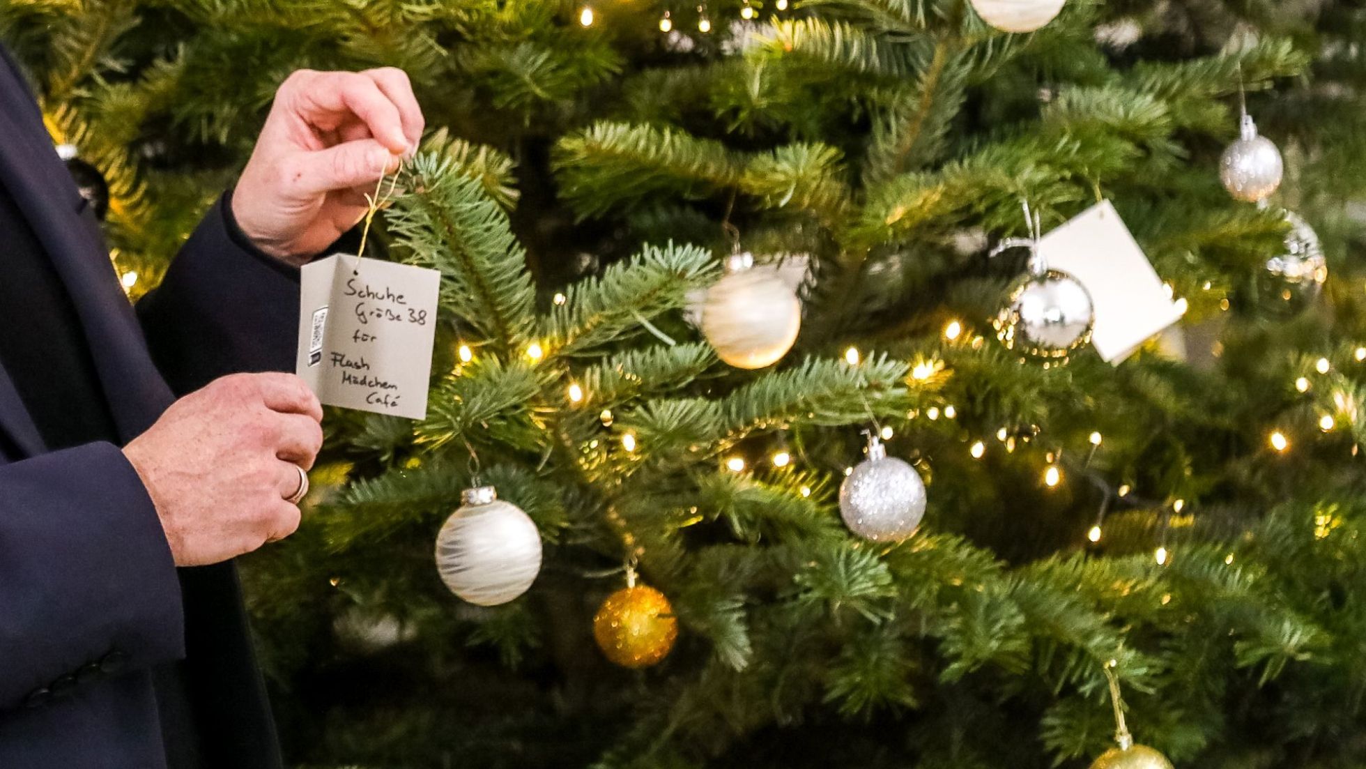 copyright: Stadt Wien / Christian Fürthner Hände halten Wunschzettel vor einem geschmückten Christbaum.